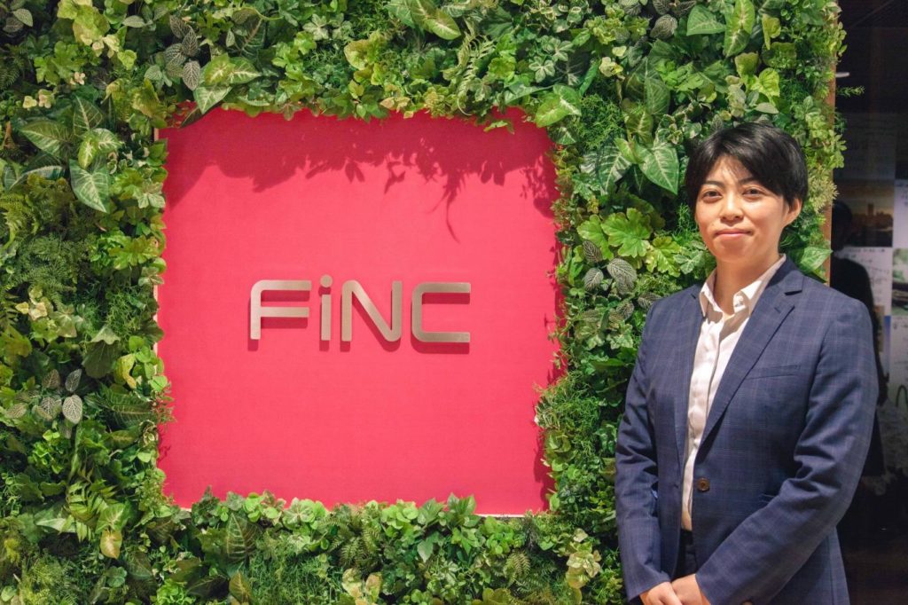 FiNCのロゴの横に立つ井上さんの画像
